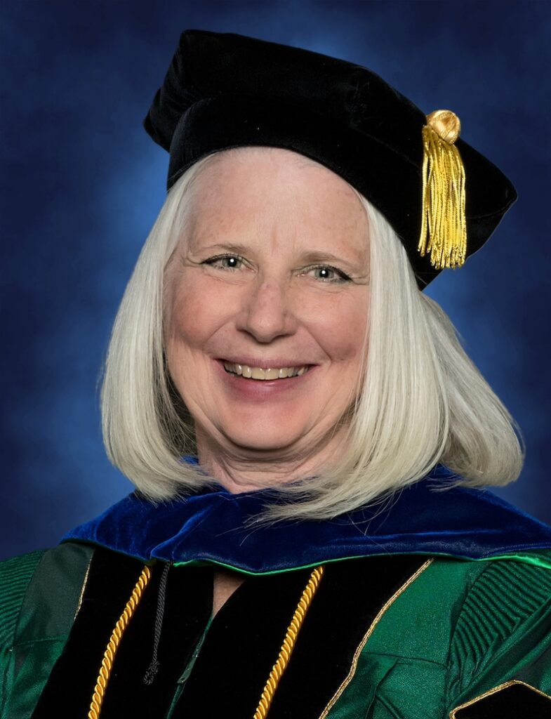 Photo of Teresa Moss in Doctoral regalia, green gown, block cap with gold tassel 